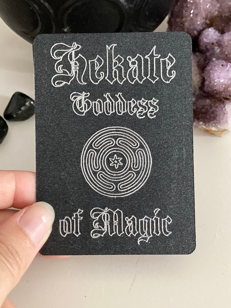K&ouml;nnte beinhalten: Schwarze Karte mit wei&szlig;em Text und einem wei&szlig;en Symbol. Der Text lautet "Hekate G&ouml;ttin der Magie".