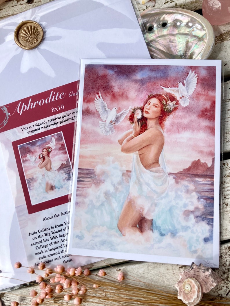 May include: Aphrodite, the Greek goddess of love and beauty, is depicted in a watercolor painting. She is standing in the ocean waves, holding a mirror and surrounded by white doves. The painting has a pink and orange sunset sky in the background.