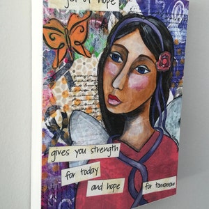 Op de afbeelding: Een kleurrijk gemengd media schilderij van een vrouw met vleugels, een vlinder en de tekst "angel of hope gives you strength for today and hope for tomorrow".