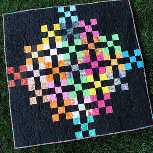 May include: A colorful quilt with a black background and a checkered pattern. The quilt is made up of squares of different colors, including red, orange, yellow, green, blue, and purple. The quilt is edged with a black and white trim.
