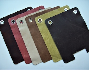 May include: Six leather swatches in different colors, each with a silver grommet. The colors are brown, red, beige, brown, green, and black.