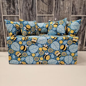 May include: A blue tissue box cover with a bee and sunflower pattern. The cover has three matching pillows with the same pattern.