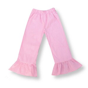 May include: Pink gingham pants with a ruffled hem. The pants have an elastic waistband.