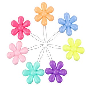 May include: A collection of colorful flower-shaped hair pins in shades of pink, orange, blue, yellow, green, and purple. Each pin has a wire stem. The pins are arranged in a circular pattern, showcasing their vibrant colors and floral design.