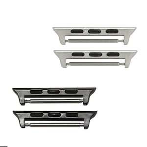 May include: A set of four watch band adapters in two colors: silver and black. Each adapter has a rectangular shape with three black oval inserts and a spring bar for attachment. The adapters are designed to connect watch bands to a watch.