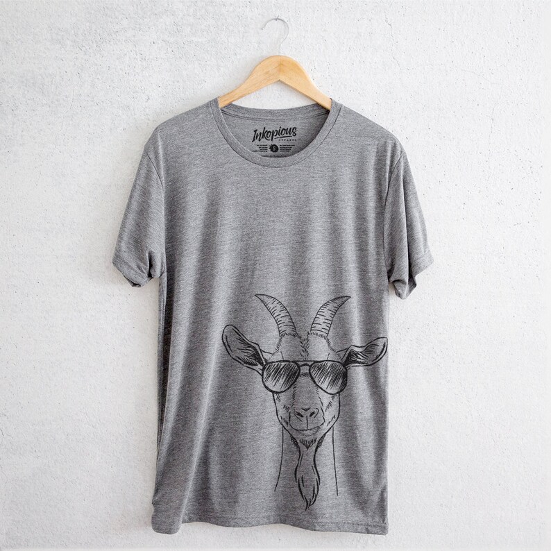 May include: A heather grey t-shirt featuring a black and white illustration of a goat wearing sunglasses. The shirt has the text "Inkspicious" printed on the front.