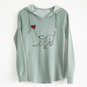 May include: A sage green hooded sweatshirt with a black and white illustration of a dog holding a red heart-shaped balloon.