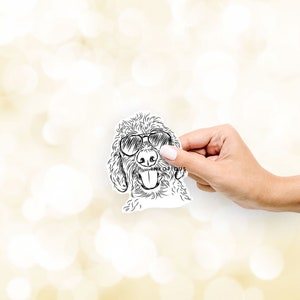 May include: A black and white line drawing of a dog wearing sunglasses. The dog is smiling with its tongue sticking out. The drawing is on a white background.