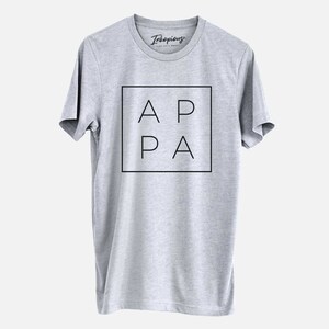 May include: Gray t-shirt with a black square graphic that says "APA" in all caps.