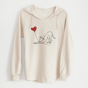 May include: A cream-colored hooded sweatshirt with a graphic of a dog holding a red heart-shaped balloon. The dog is drawn in black outline.