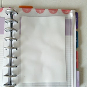 May include: A clear plastic pocket with a zipper closure is attached to a planner. The pocket is designed to hold papers or other small items. The planner has a silver binding and is labeled with the months of May, June, July, and April.