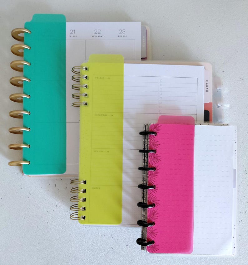 Pu&ograve; includere: Un assortimento di agende colorate con rilegatura a spirale. Le agende sono nelle tonalit&agrave; di verde acqua, giallo e rosa, con accenti oro e neri. Le pagine sono a righe e includono layout di calendario.