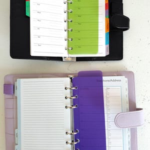 Pu&ograve; includere: Due organizer personali aperti. Quello superiore &egrave; nero con un divisore settimanale verde. Quello inferiore &egrave; lavanda con un divisore viola con l'etichetta "Telefono/Indirizzo". Entrambi hanno pagine a righe e rilegatura ad anelli metallici.