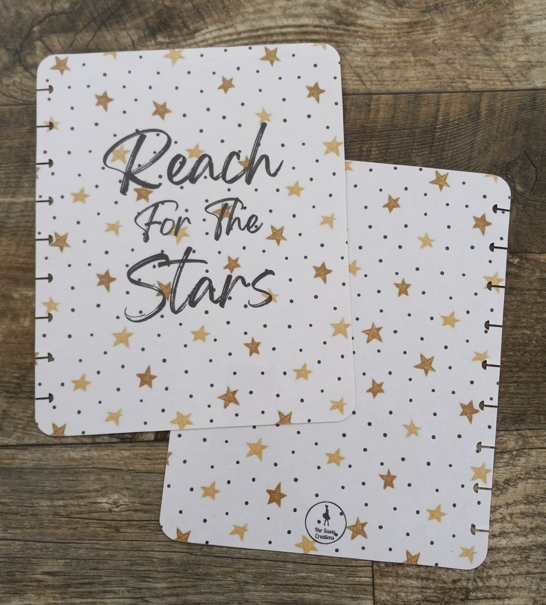 May include: Two white pages with a gold star pattern and black dots. The top page has the text "Reach for the Stars" in black cursive writing. The bottom page has a small black and white logo that says "Star Sized Creations".