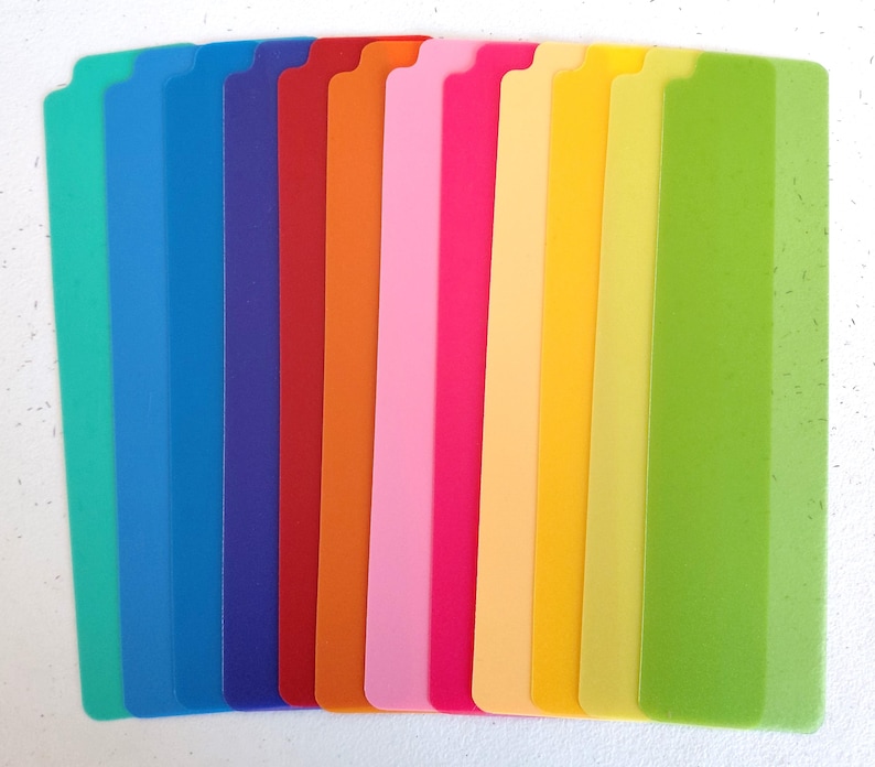 Pu&ograve; includere: Una collezione di divisori in plastica rettangolari colorati. I divisori sono disposti verticalmente, mostrando sfumature di verde, blu, rosso, arancione, rosa e giallo. Ogni divisore ha una parte superiore dentellata, su uno sfondo bianco.