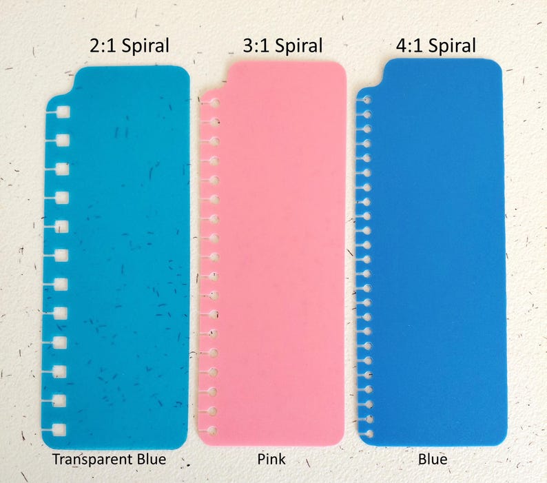 Pu&ograve; includere: Tre strumenti di rilegatura in plastica blu e rosa. Gli strumenti sono etichettati con il testo "2:1 Spiral", "3:1 Spiral" e "4:1 Spiral". I colori sono blu trasparente, rosa e blu. &Egrave; visibile anche il testo "Transparent Blue", "Pink" e "Blue".