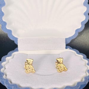Peut inclure: Une paire de boucles d'oreilles à clous en or en forme de petits ours en peluche. Chaque boucle d'oreille présente une surface texturée représentant les traits du visage, les oreilles et les membres de l'ours. Présentées dans un écrin bleu clair.