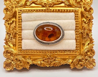 Spilla vintage in argento sterling con ambra baltica di metà secolo, cabochon ovale in ambra color cognac, bordo a corda in argento 925.