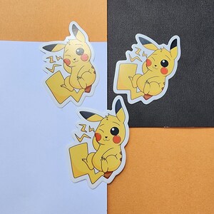 May include: Three yellow Pikachu stickers with a winking face and a lightning bolt behind them. The stickers are on a white, orange, and black background.