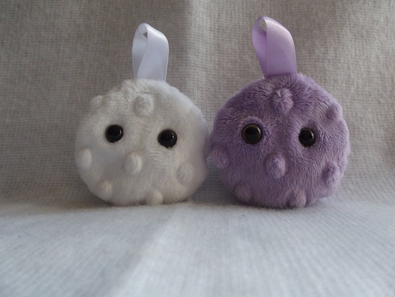 May include: Two plush toys shaped like round balls with googly eyes. One is white with white dots and the other is purple with purple dots.