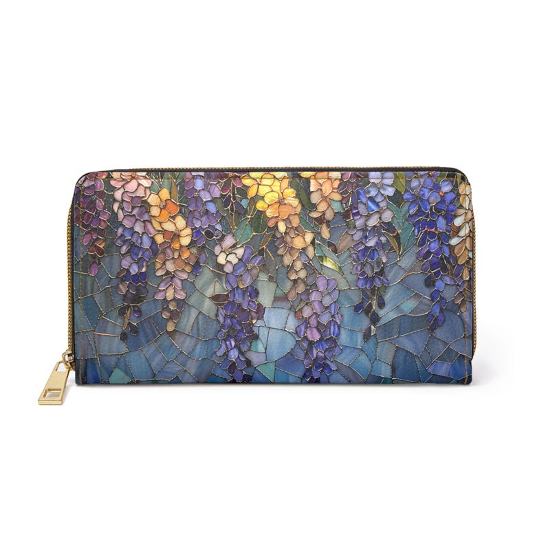 May include: A zippered wallet featuring a colorful floral design. The wallet's pattern showcases a mosaic-like depiction of wisteria blossoms in shades of purple, yellow, and orange against a blue background. The wallet has a gold-colored zipper and pull.