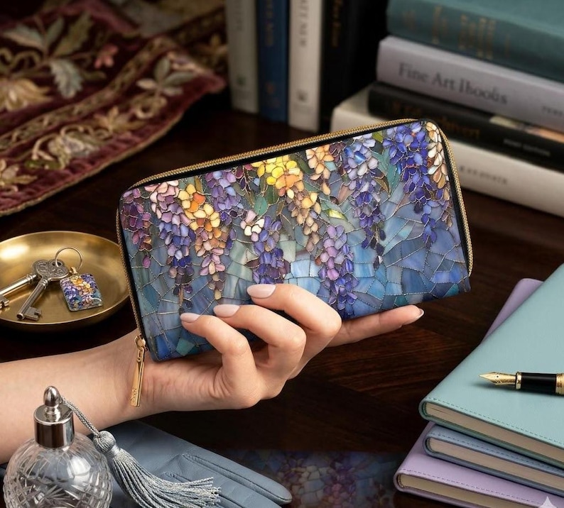 May include: A rectangular zip-around wallet with a mosaic-style floral design in shades of purple, blue, yellow, and green. The wallet has a gold-colored zipper and a matching pull tab.