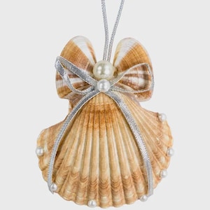 May include: A hanging ornament crafted from a natural tan and brown ridged seashell. The shell is adorned with a silver metallic ribbon tied in a bow, featuring two white spherical beads at the center and smaller beads along the scalloped edges.