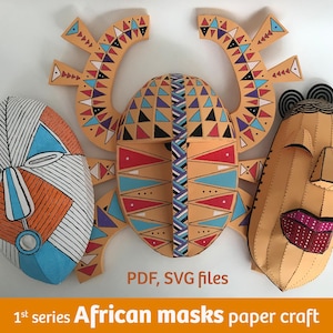 Puede incluir: Tres máscaras africanas de papel de colores. Las máscaras son en tonos naranja, azul y blanco, con patrones geométricos. El texto "PDF, SVG files" y "1st series African masks paper craft" es visible.