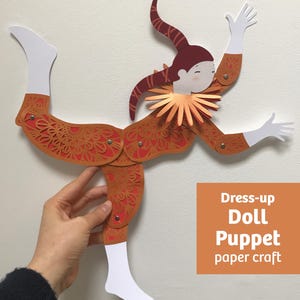 Puede incluir: Una marioneta articulada de papel con forma de bufón, con gorro granate, cuerpo naranja estampado y manos y pies blancos. La figura presenta un cuello con volantes y remaches metálicos en las articulaciones. Texto: Dress-up Doll Puppet paper craft.