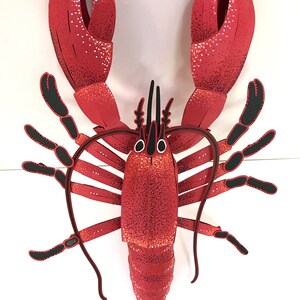 Peut inclure: Un homard rouge avec des pinces et des antennes noires. Le homard est en papier et a une finition paillet&eacute;e.