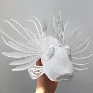 May include: A white paper sculpture of a lionfish with intricate details and a textured surface.