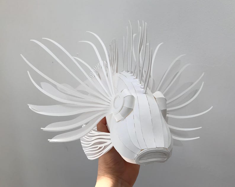 May include: A white paper sculpture of a lionfish with intricate details and a textured surface.