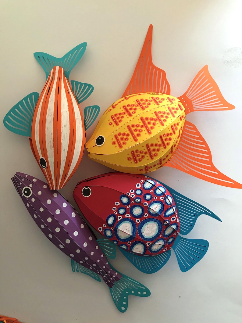 May include: Four decorative paper fish sculptures. One is orange and white striped with teal fins, one is yellow with red dotted patterns and orange fins, one is purple with white polka dots, and one is red with blue and white circular patterns.