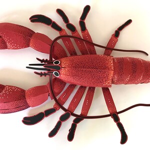 Peut inclure: Un homard en papier rouge avec des pattes et des yeux noirs. Le homard est fait de papier et a une surface textur&eacute;e.
