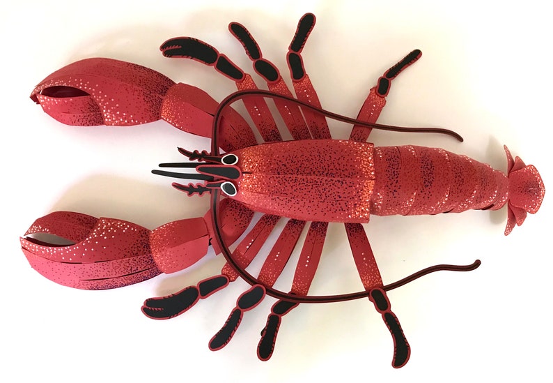 Peut inclure: Un homard en papier rouge avec des pattes et des yeux noirs. Le homard est fait de papier et a une surface textur&eacute;e.