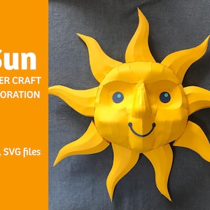 Puede incluir: Un sol de papel amarillo con una cara sonriente y ojos azules. El sol tiene un efecto 3D y es una decoración de papel. El texto "Sun Paper Craft Decoration PDF, SVG files" está en la parte inferior de la imagen.