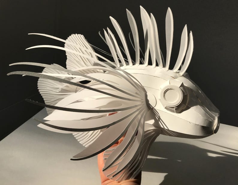 May include: A white paper sculpture of a lionfish with intricate details and a realistic appearance.