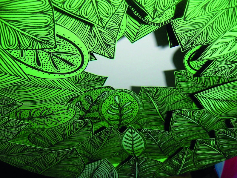 May include: A green and black patterned design with a white background in the center. The design is made up of leaves and other organic shapes.