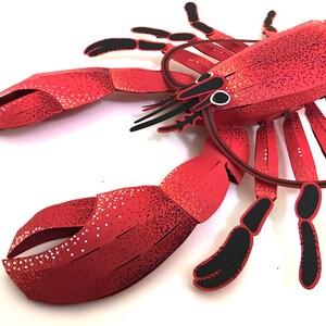 Peut inclure: Un homard en papier rouge avec des d&eacute;tails noirs. Le homard est fait de papier et a un effet 3D. Le homard est un projet d'artisanat populaire pour les enfants et les adultes.