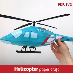 Puede incluir: Un modelo de helicóptero de papel en tonos turquesa, blanco y rojo. El modelo presenta un rotor principal, un rotor de cola y un tren de aterrizaje. El texto en la imagen dice "PDF, SVG files" y "Helicopter paper craft".