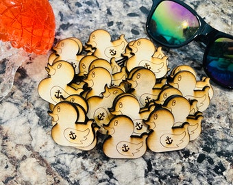 May include: A pile of wooden duck ornaments with an anchor design. The ducks are light brown and have a distressed look.