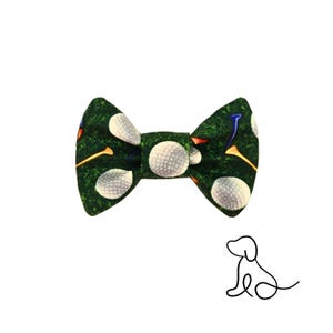 May include: A green bow tie with a golf ball and tee pattern. The bow tie features white golf balls and colorful tees on a green background. A line drawing of a dog is in the lower right corner.
