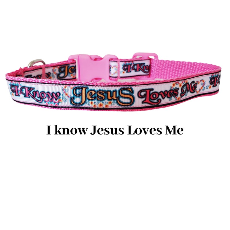 May include: Pink dog collar with a white background and the text "I know Jesus Loves Me" in black and colourful lettering.