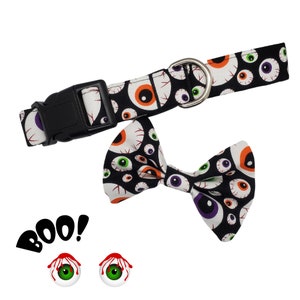 May include: A black and white dog collar and bow tie with a spooky eye pattern. The collar has a black buckle and the bow tie is tied in a classic bow shape. The text "BOO!" is printed in red and white on a white background. Two green eyes with red bloodshot veins are also included in the image.