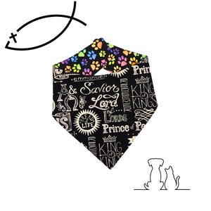 May include: Black and white dog bandana with religious text and paw prints. The bandana features the words "Savior Lord" and "King of Kings" in a decorative font. The top edge has colorful paw prints.