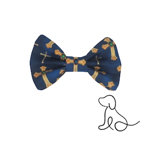 May include: A navy blue bow tie with a repeating pattern of gold crosses, each adorned with a green gem. The bow tie is a stylish accessory for pets.