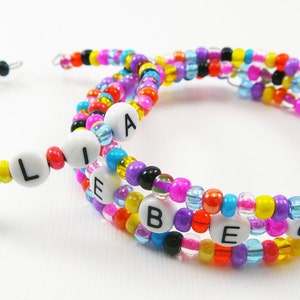 May include: Two colorful beaded bracelets with the names "JULIA" and "REBECCA" spelled out in white beads.