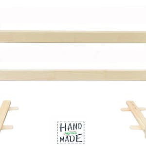 May include: A natural wood bed rail with two horizontal bars and a small green sticker with the text "HAND MADE" on the top right corner.