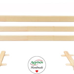 May include: A light-colored wooden headboard with three horizontal slats. The headboard has a rectangular shape with angled legs and a small logo on the upper right corner. The base has a support structure. The logo says "AgSeDaJu Handmade".