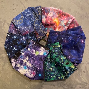 May include: A set of six face masks featuring different galaxy and constellation prints. The masks are made of a soft, breathable fabric and have adjustable ear loops.